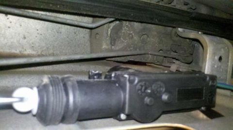 1982 Ford Bronco - A close-up view of a black door lock actuator mechanism with a metal rod extending from it, attached to the interior door latch assembly of…