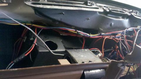 1982 Ford Bronco - A close-up view of a complex wiring harness behind the dashboard of a vehicle. Various colored wires are bundled together with zip ties and…