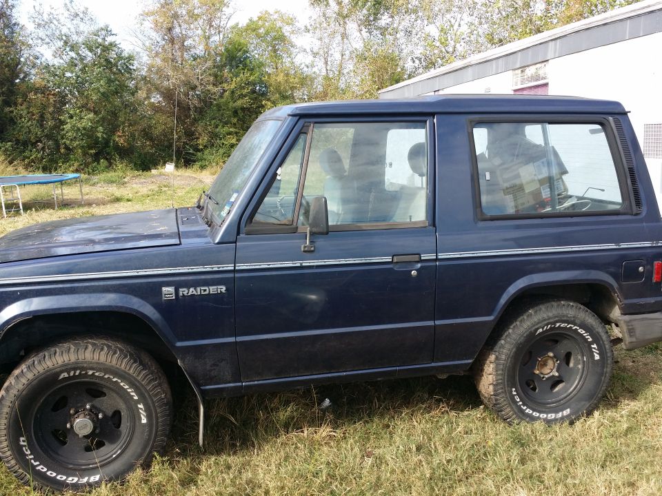Side view of a dark blue two-door SUV with Raider badging and All-Terrain T/A tires.