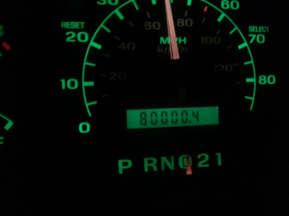 Car dashboard at night: speedometer showing 70 MPH, odometer reading 80000.4, and gear selector 'P R N D 2 1'.