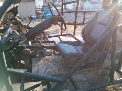 1986 Ford Bronco - Interior view of a custom-built vehicle, possibly a dune buggy or sand rail, showing a black leather seat, steering wheel, and transmission…