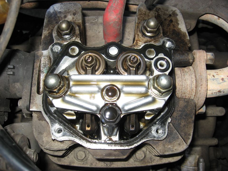 Close-up of motorcycle engine valve train with rocker arms and valves.