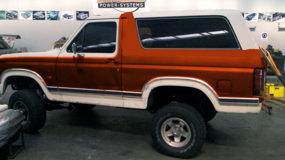 White and orange two-tone Ford Bronco side view in a garage