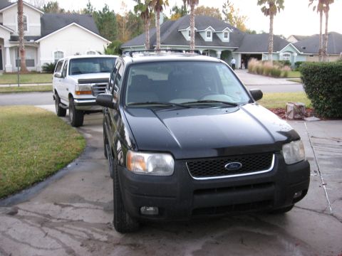 1994 Ford Bronco - A black Ford SUV is parked in a driveway in front of a white Ford SUV. The black SUV is in the foreground, showing its front end and driver…