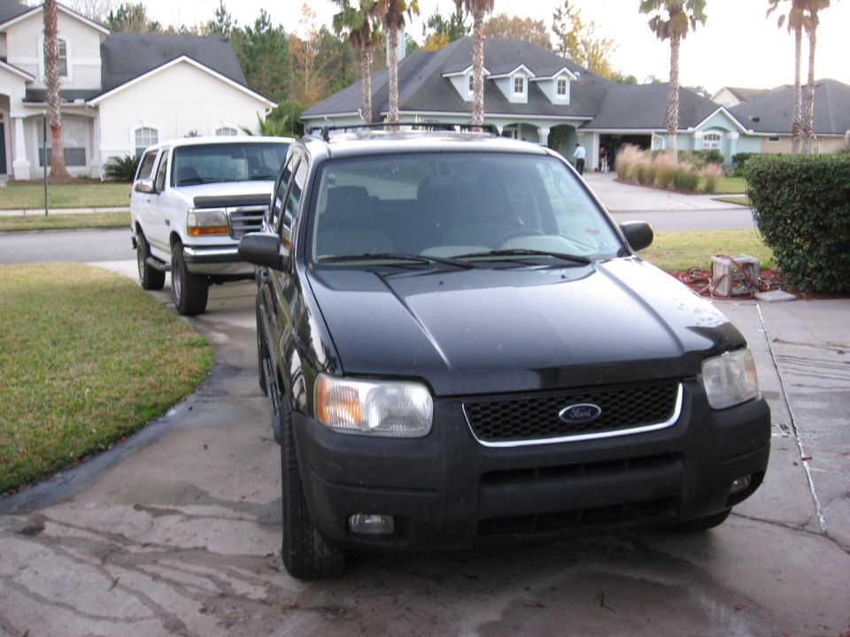 Black Ford SUV parked in driveway, driver's side and front visible.