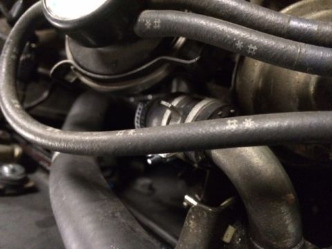 1988 Suzuki Samurai - A close-up view of engine components and hoses within a vehicle's engine bay.
