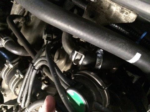 1988 Suzuki Samurai - Close-up view of an engine bay, showing various hoses, clamps, and a green cap. A thumb is also visible in the frame.