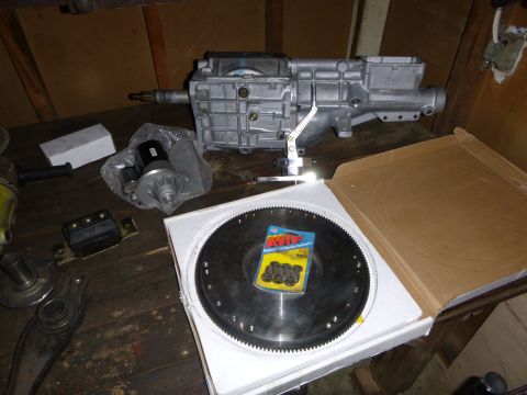 1953 Plymouth Belvedere - Manual transmission, starter motor, and flywheel are laid out on a wooden surface.