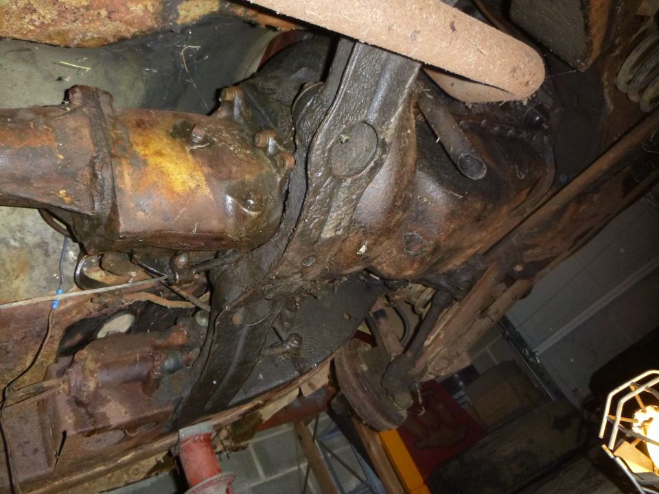 Rusty undercarriage showing differential, driveshaft, and suspension components