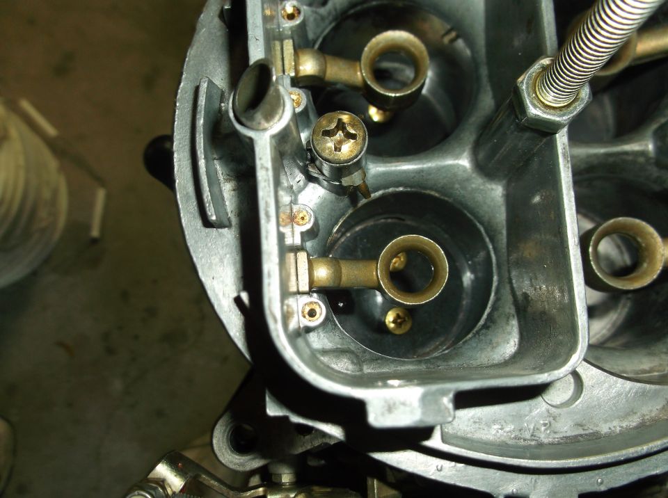 Close-up of a carburetor's internal components, showing brass fittings and screws
