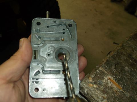 1979 Ford Ranchero - A drill bit is shown entering a carburetor part held by a hand, suggesting a modification or repair.