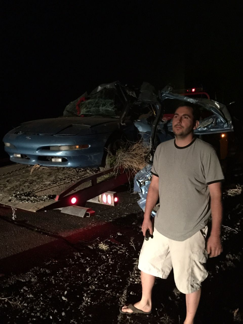 Blue 1993 Ford Probe, heavily damaged, on a tow truck at night