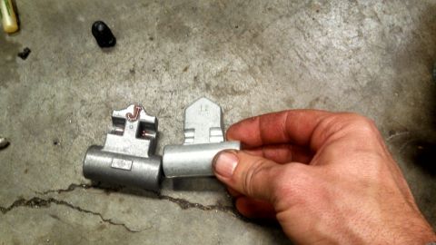 1967 Ford F-250 - A hand holds two metal automotive parts, one marked with a 'J', on a concrete surface.