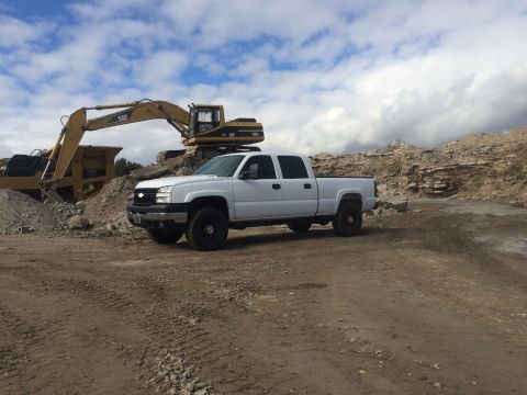 2006 Chevrolet Silverado 2500 - A white 2006 Chevrolet Silverado 2500 is parked at a construction site with heavy machinery in the background.