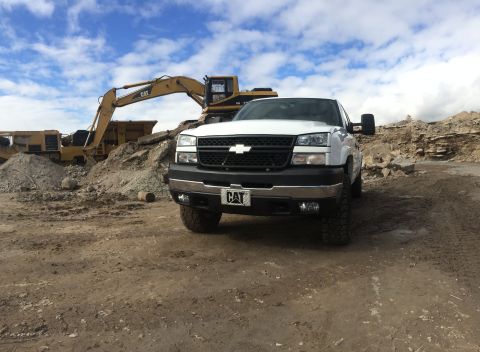 2006 Chevrolet Silverado 2500 - A white 2006 Chevrolet Silverado 2500 pickup truck is parked at a construction site, with heavy machinery in the background.
