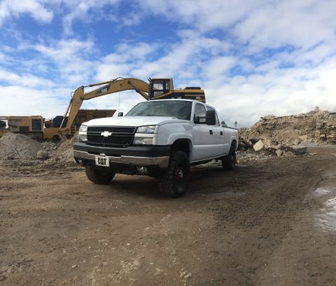 2006 Chevrolet Silverado 2500 - 2006 Chevrolet Silverado 2500 parked in front of construction equipment under a cloudy sky.
