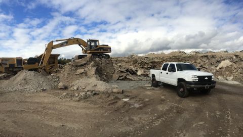 2006 Chevrolet Silverado 2500 - A white Chevrolet Silverado pickup truck is parked on a dirt road at a construction site with heavy machinery in the background.