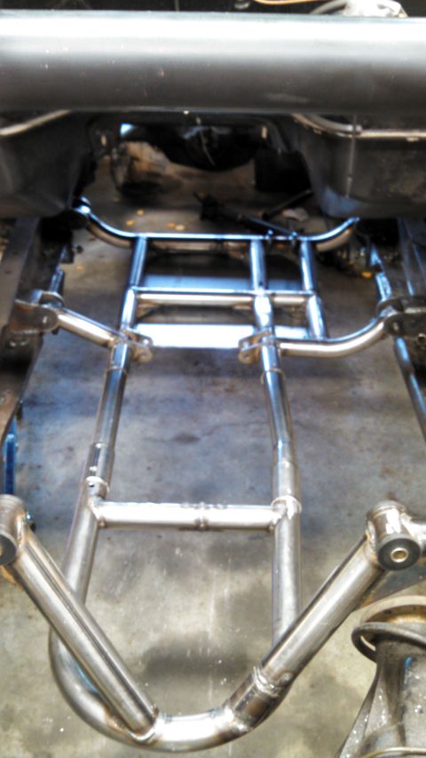 1967 Ford F-250 - Close-up view of a custom exhaust system installed on a vehicle frame, showing intricate pipework and suspension components.