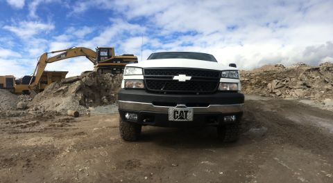 2006 Chevrolet Silverado 2500 - A white Chevrolet Silverado pickup truck is parked in front of a construction site with heavy machinery in the background.