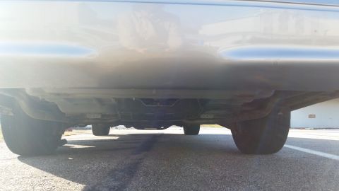 1991 Ford LTD Crown Victoria - The underside of a silver vehicle is captured from a low perspective, revealing the exhaust system and wheels.