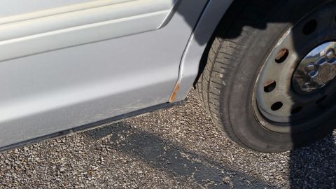 1991 Ford LTD Crown Victoria - Close-up of a car's side panel and wheel shows signs of rust and wear.