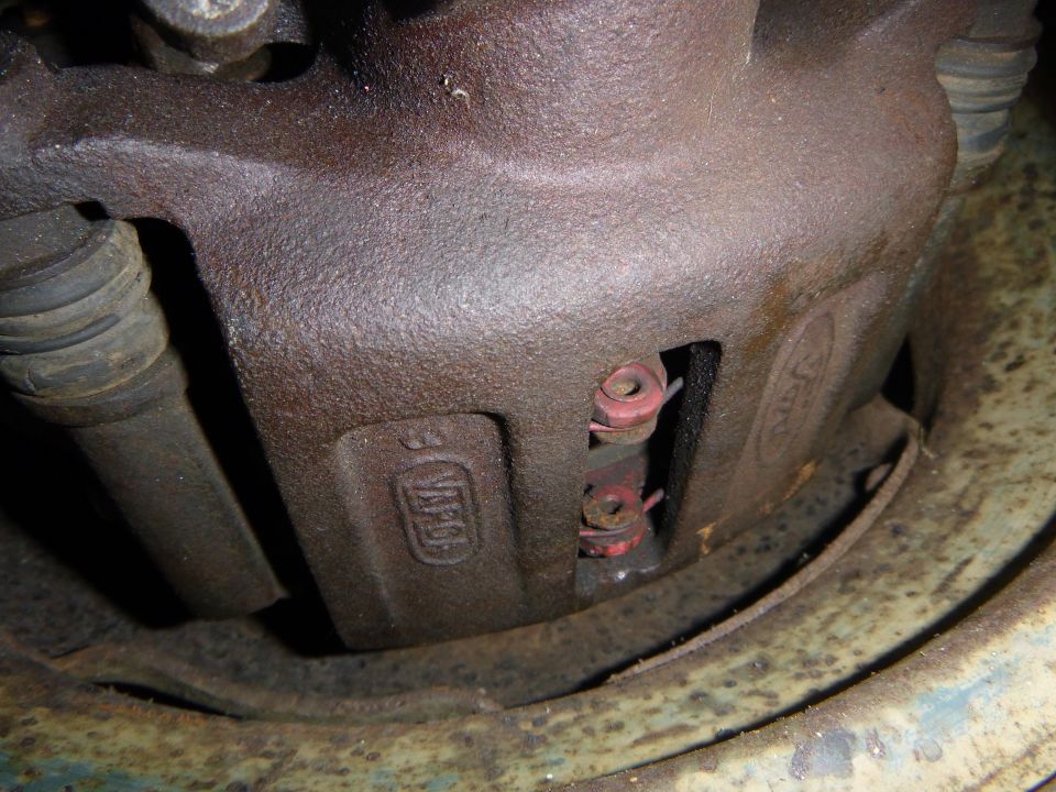Rusty brake caliper with visible Ford logo and part numbers