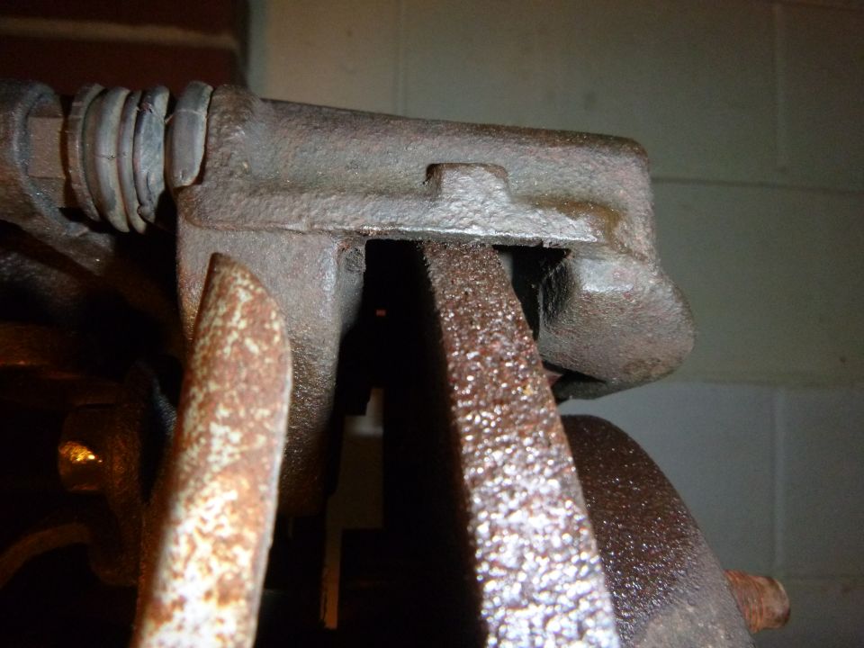 Close-up of a rusty brake caliper assembly with a brake rotor visible