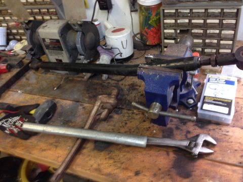 1979 Ford Bronco - Tie rod assembly clamped in a vise on a workbench with various tools and parts.