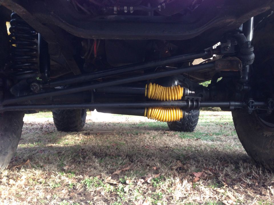Undercarriage view of yellow-booted steering components and suspension parts on a vehicle