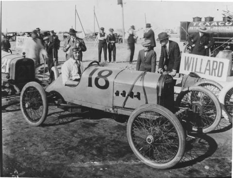 1909 Ford Model T - A race car, identified by the number 18 on its side, is prepared for an event, with a Willard sign and a Texaco tanker visible.