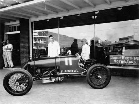 1909 Ford Model T - A vintage racing car is displayed outside a building with a "DODGE BROTHERS MOTOR CARS" sign in the window.