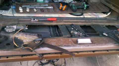 1982 Ford Bronco - Tools and parts are laid out next to a disassembled car door, ready for repair.