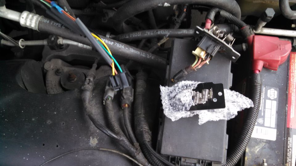 New blower motor resistor on bubble wrap in engine bay next to battery, old resistor and connector unplugged