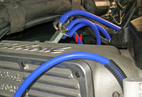 1990 Ford Bronco - Blue spark plug wires connected to an engine valve cover that reads 'Edelbrock PERFORM'.
