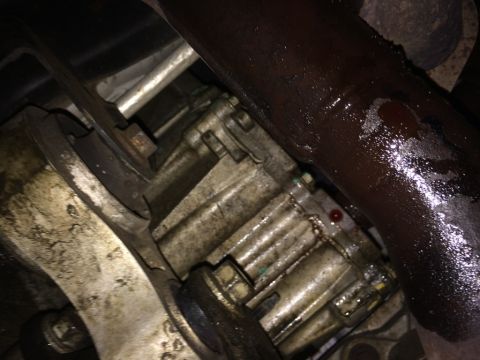 2011 Ford Elite - Close-up view of a vehicle's transfer case and exhaust pipe, showing signs of a fluid leak.