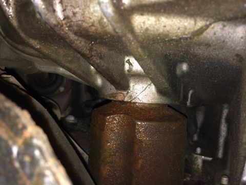 2011 Ford Elite - Close-up view of a rusted oil filter and transmission housing, indicating potential leaks.