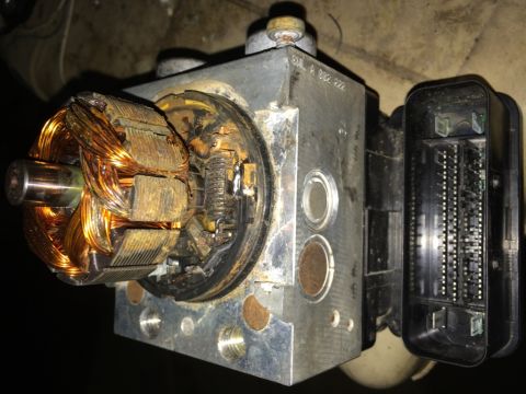 2011 Ford Elite - Close-up of an ABS pump motor, highlighting its internal components and external electrical connections.