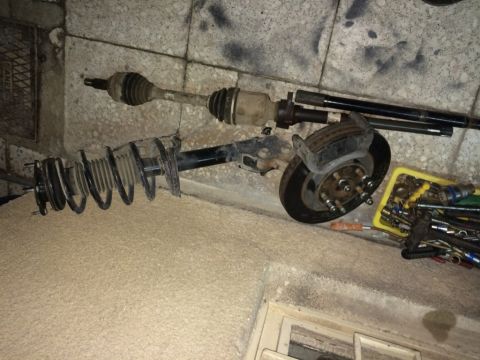 2011 Ford Elite - A drive axle, strut assembly, and brake rotor are laid out next to a yellow container filled with tools.