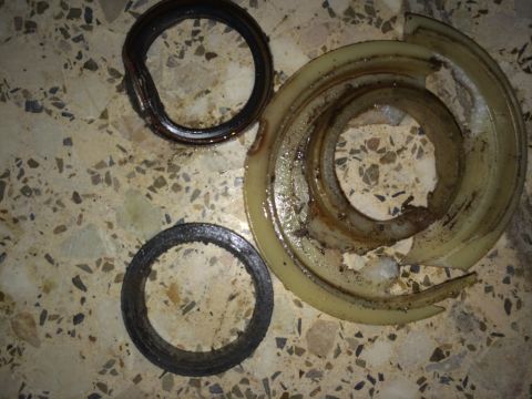 2011 Ford Elite - The image displays three automotive parts, including two seals and a fractured plastic component, resting on a speckled tiled floor.