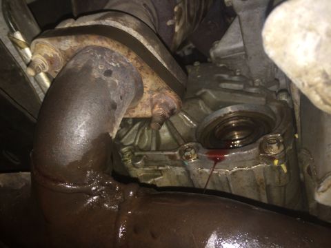 2011 Ford Elite - Close-up view of a vehicle's exhaust pipe and transmission housing, showing a leaking seal.