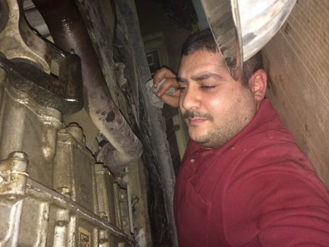 2011 Ford Elite - Mechanic works on the drivetrain of a vehicle, focusing on the PTU and intermediate shaft area.