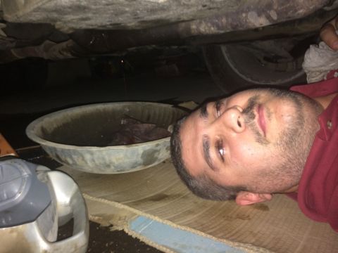 2011 Ford Elite - Man working on car maintenance, with an oil pan catching fluid from underneath.