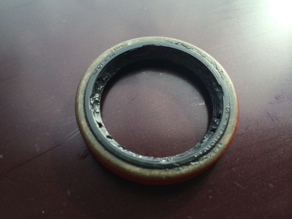Close-up of a worn automotive seal with visible damage and debris