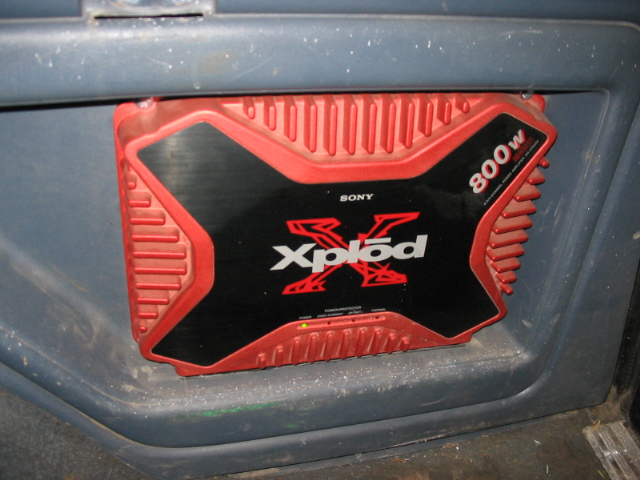Red and black Sony Xplod 800w car amplifier mounted in a gray plastic panel