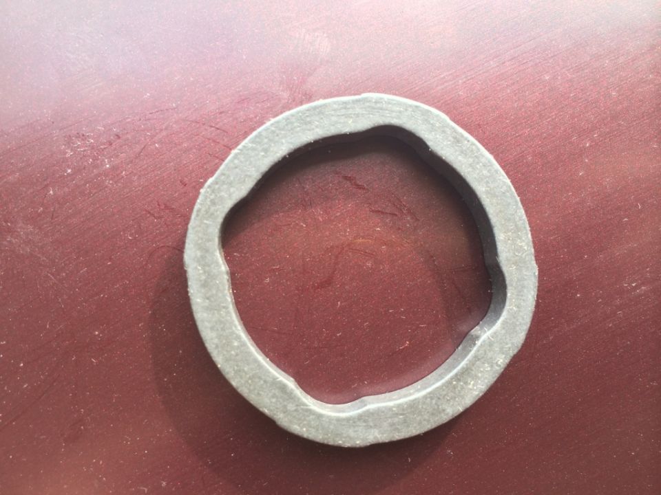 Close-up of a rubber gasket on a red surface. Supermotors.net logo in the bottom right