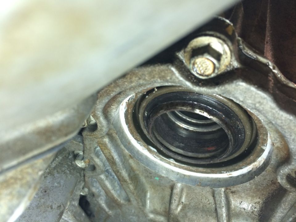 Close-up of a worn seal within a metal housing, with visible grease and dirt