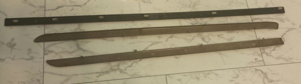 Three automotive trim pieces laid out on a tiled surface