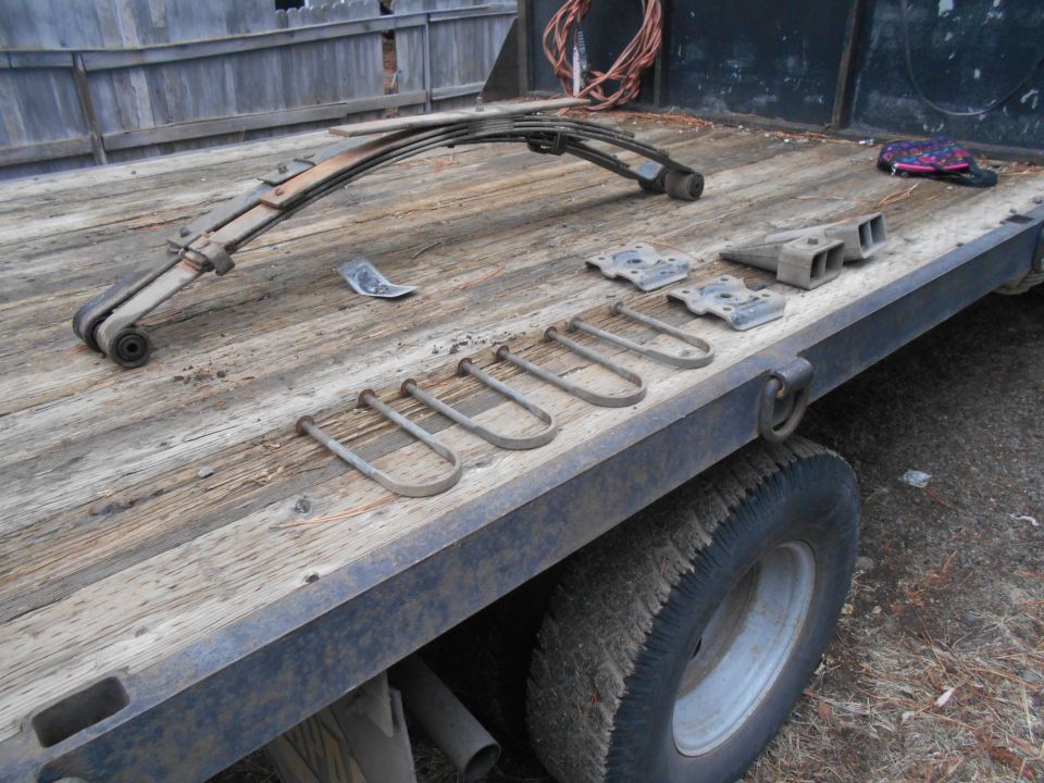 Leaf springs and U-bolts laid out on a wooden flatbed truck deck