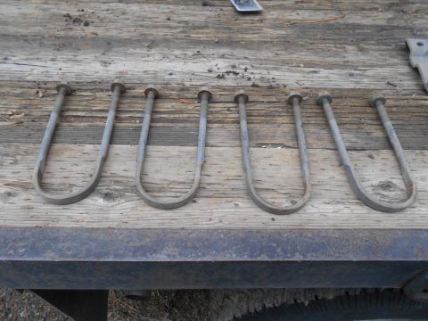 1995 GMC Safari - Six U-bolts are laid out on a weathered wooden surface, possibly for vehicle suspension.