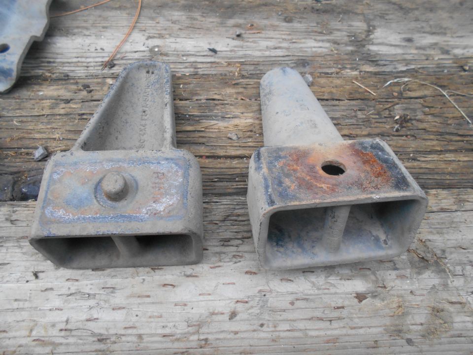 Two metal lift blocks with visible part numbers and rust on a wooden surface